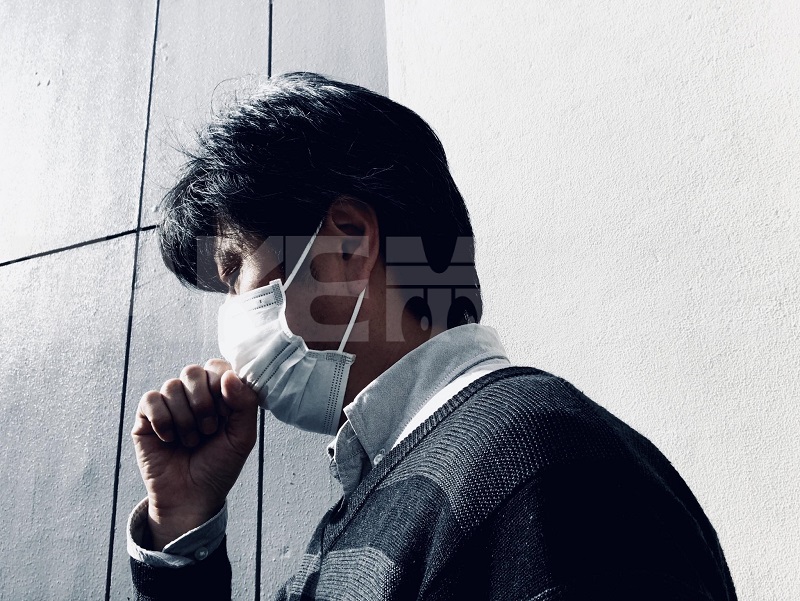 新型コロナウイルス?インフルエンザ?咳が出るのを我慢できないマスク姿の男性のイメージ無料写真